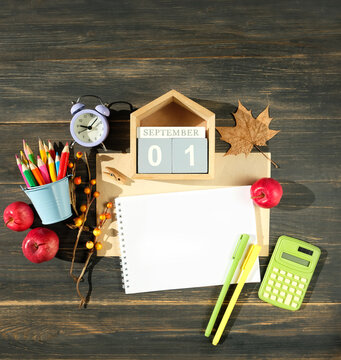 September calendar. calendar block with date 1 September, alarm clock, pencils, empty notepad, school supplies, apples on wooden table. Back to school, beginning of the school year, Knowledge Day.
