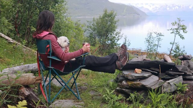 Woman, drinking coffee in the morning in front of a tent, wild camping in nature, Norway, morning, sunny morning