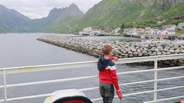 Cute child, enjoying ferry ride between Senja and Andenes Andoya summertime, child and adults on a ferry on sunset