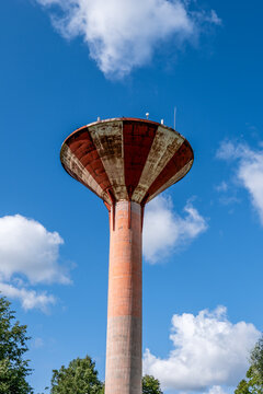 Weathered Red and White Water Tower Against Bright Blue Sky