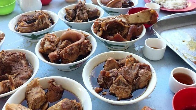 People enjoying authentic and original Klang bak kut teh herbal stewed pork served in multiple small bowls in restaurant. Each bowl consist different pork parts.