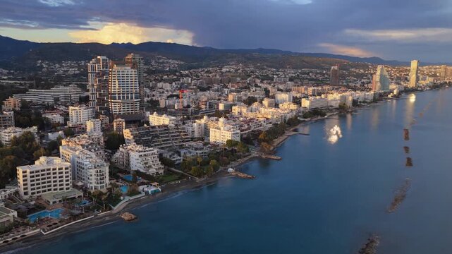 Aerial view of limassol cyprus, tracking shot captures coastal city buildings, reflecting golden hour sunlight on tranquil mediterranean sea.