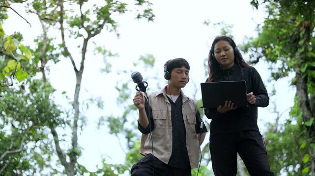 Sound Recordists Capturing Forest Ambience with Microphone and Laptop Outdoors