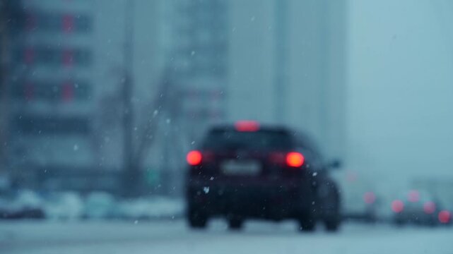 heavy snowfall and snowstorm in city with car traffic on icy road, vehicles driving through snowy streets during winter weather 4k