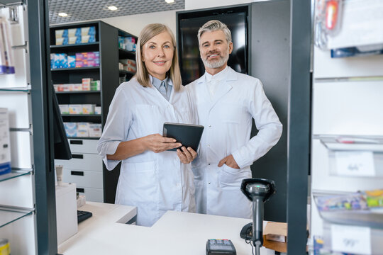 Man and woman in lab coats working together in the pharmacy