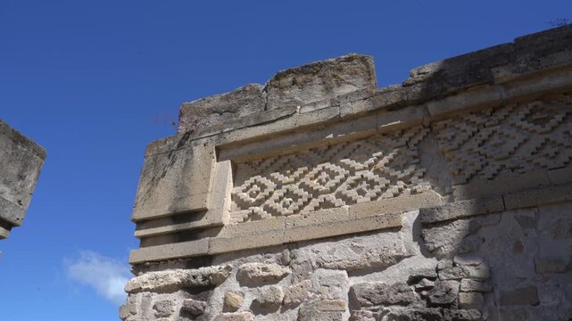 Static low angle shot of ancient Zapotec stone wall detail with geometric fretwork mosaic at Mitla archaeological site in Oaxaca, Mexico.