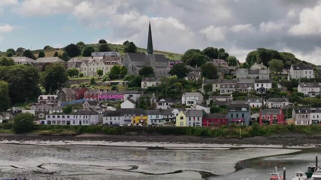 An authentic aerial perspective of the colorful coastal village of Crosshaven in Ireland, featuring traditional architecture and a prominent church spire overlooking the harbor.