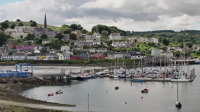 A scenic drone shot capturing the colorful houses, church spire, and sailboat marina of Crosshaven, Ireland. Perfect for travel documentaries and European tourism content.