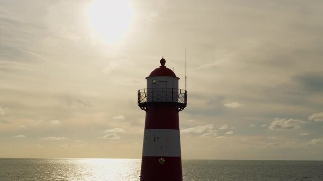 Lighthouse next to the sea. Behind the sun.