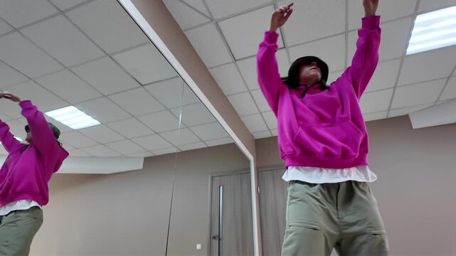 Young Woman in Pink Hoodie and Bucket Hat Dancing Freestyle in a Modern Apartment