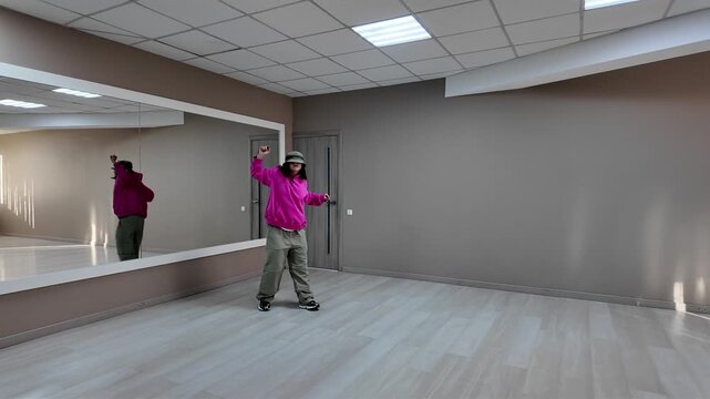 Young Woman in Pink Hoodie and Bucket Hat Dancing Freestyle in a Modern Apartment