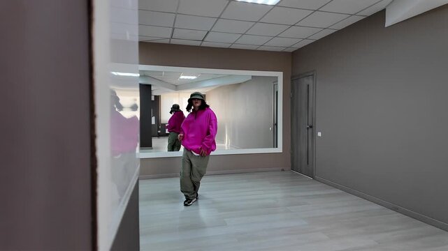 Young Woman in Pink Hoodie and Bucket Hat Dancing Freestyle in a Modern Apartment