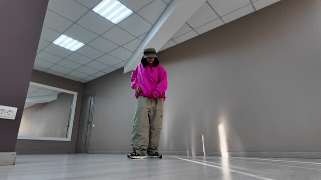 Young Woman in Pink Hoodie and Bucket Hat Dancing Freestyle in a Modern Apartment