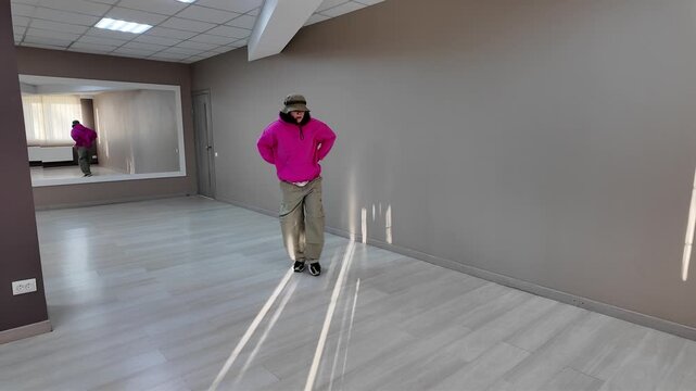 Young Woman in Pink Hoodie and Bucket Hat Dancing Freestyle in a Modern Apartment