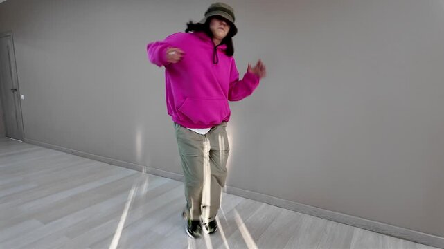 Young Woman in Pink Hoodie and Bucket Hat Dancing Freestyle in a Modern Apartment