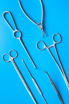 A lot of stainless surgical instruments and tools on blue table, top view. Medical background