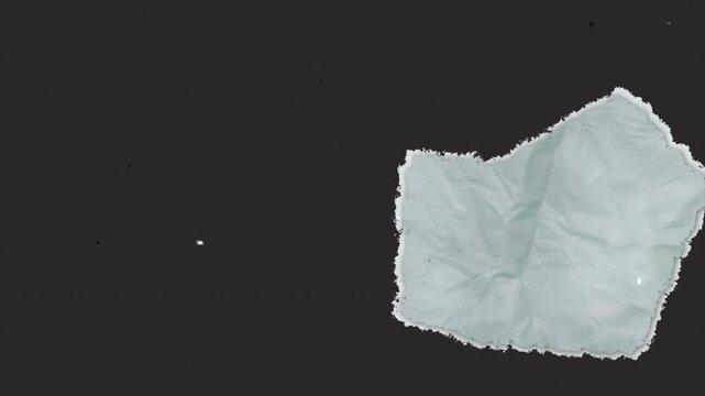 A close up view of a crumpled piece of white paper against a dark grey background.