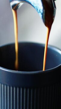 A skilled barista expertly pours rich espresso into a dark cup, creating a perfect crema. The aroma fills the air in the bustling cafe, where patrons enjoy their morning routine.