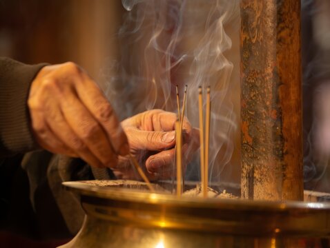 Hands lighting incense sticks in a temple