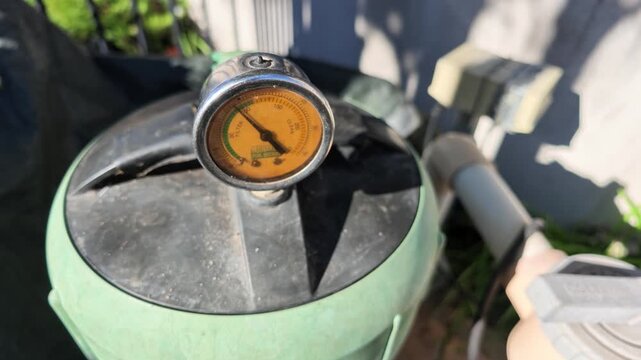Close-up view of a pressure gauge on a swimming pool sand filter, indicating the system's operational pressure and need for maintenance
