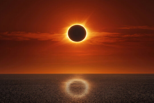 Spectacular Total Solar Eclipse over Ocean at Sunset with Fiery Orange Sky and Bright Reflection on Water