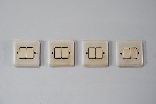 Row of four old double light switches on a white wall for home electrical control