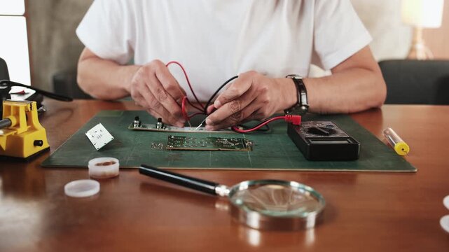Close-up, man's hand with multimeter tool, voltage test, disassembling circuit board, focusing on precision checks for electrical appliance DIY fixes, electronics component hobby, handyman workshop.