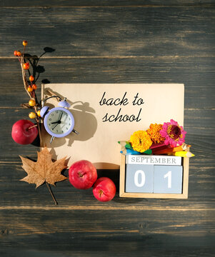 Back to school background. September calendar. calendar block with date 1 September, flowers, alarm clock, pencils, apples on wooden table. beginning of the school year, education, Knowledge Day.