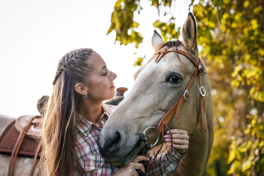 Female rancher bonding with horse on pasture. Woman standing close to her horse. Connection between people and animal