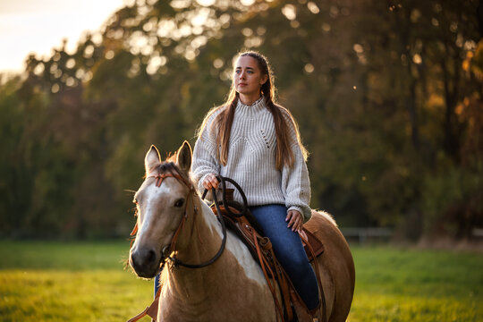 Woman riding horse on pasture. Cowgirl enjoying horseback riding and western lifestyle at countryside