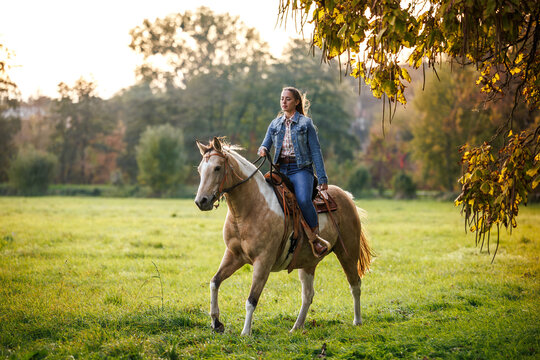 Woman riding horse at meadow. Cowgirl enjoying horseback riding and western lifestyle at countryside