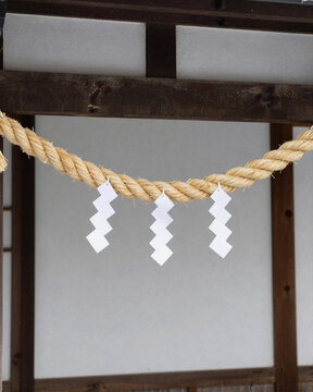 Twisted straw rope with white paper streamers hung at a house entrance for new year