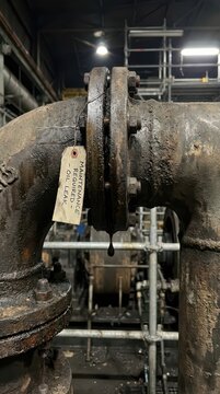Rusty flanged pipe leaking oil with maintenance tag for wind turbine inspection report background