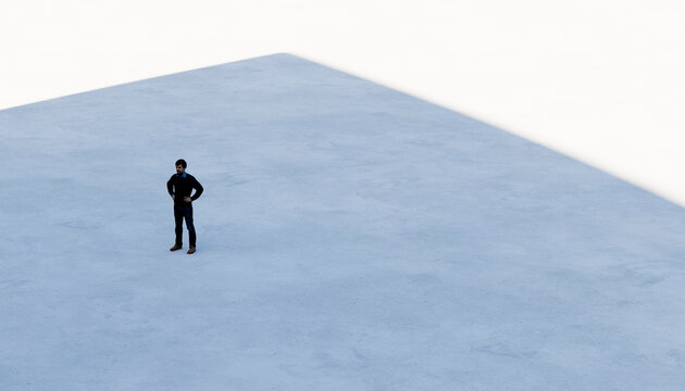 A man standing alone on a large concrete floor with shadow