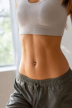 Toned female belly with navel piercing and fit abdominal muscles