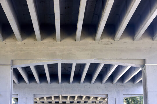 Concrete bridge underside showcasing modern infrastructure engineering, geometric parallel beams, architectural symmetry, industrial design, concrete girders, minimal construction elements.