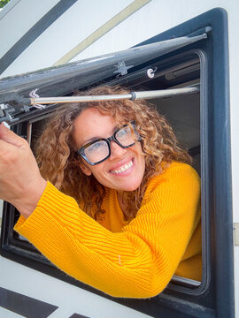 Smiling woman leaning out of camper window in yellow sweater