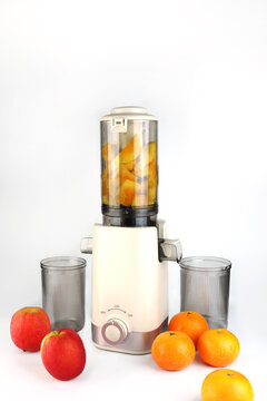 Modern juicer or juice extractor for juice or slow juice for extracting fresh fruit juice from apples and oranges featuring compact design clear containers and fresh ingredients for healthy nutrition