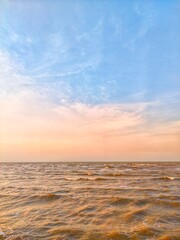 Obraz premium Golden sunset over the ocean with glowing reflections, gentle waves, and colorful sky creating a peaceful coastal landscape and tranquil nature background.