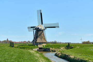 Dutch heritage and sustainable energy drainage mill Rispens in Oostereind Friesland Nederland with green fields and clear blue sky Traditional architecture and rural landscape © VeugerStock