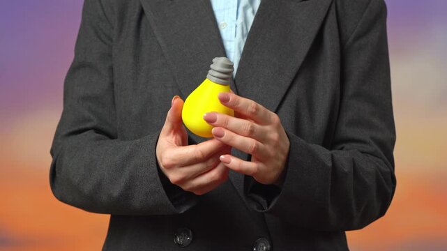 An idea lightbulb in hands of a business woman. Innovations that shatter conventions and the business order. Creative disruption challenges established markets. New thinking forces companies