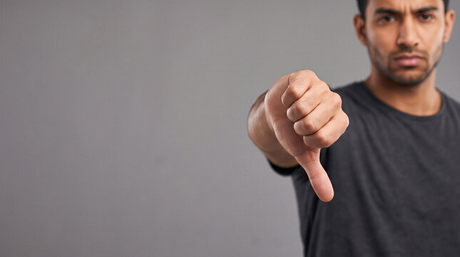 Disappointed man showing thumbs down gesture with negative expression