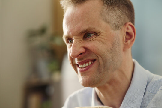 Middle aged Caucasian man smiling during conversation, showing positive emotion. Close up shot ideal for mental wellbeing campaigns, dental care marketing or healthcare services