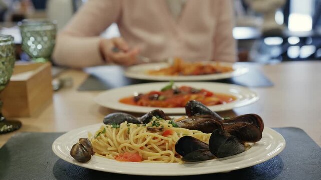 Plate of delicious spaghetti with mussels served on table in restaurant setting.