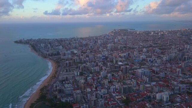 Wide panoramic drone view panning right over the city of Macei&oacute; as late sunset light reflects off the open ocean. Shot in 4K at 25 fps.