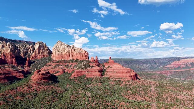 Cinematic Aerial flight toward the Giant Red Rocks of Sedona Arizona. Slowly gliding over the Coconino National Forest revealing a stunning view of these magnificent formations.