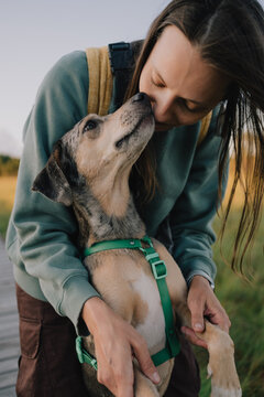 Woman embracing dog in harness during affectionate close-up outdoors