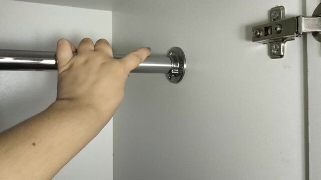 Person checking the stability of a closet rod inside wardrobe, furniture assembly, storage organization and home improvement concept.