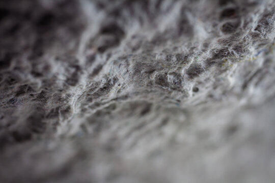 Extreme close up of old gray handmade paper clay with a structure and rough texture. Paper recycling. Selective soft focus, shallow depth of field.