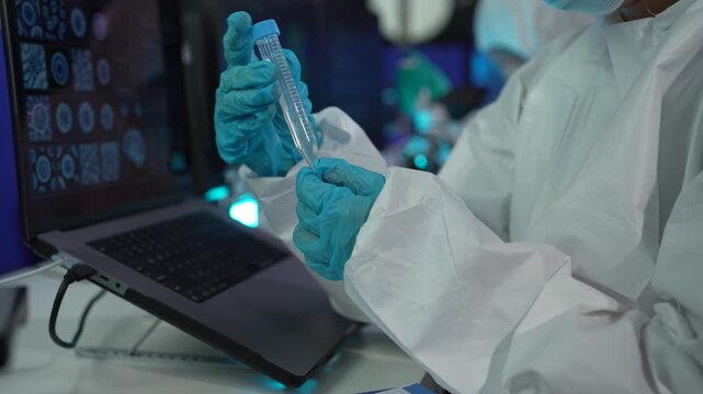 Biomedical researchers wearing PPE kit working with microscope and chemical samples for vaccine development and disease research.